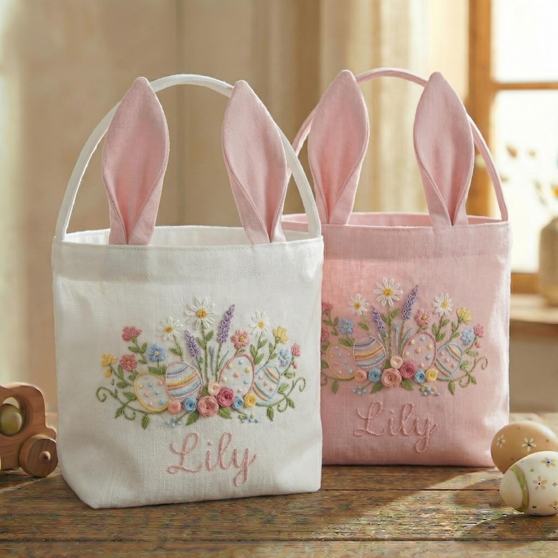 May include: Two Easter-themed tote bags with bunny ears. One is white, the other is pink. Both bags have embroidered floral and Easter egg designs, with the name "Lily" embroidered below. The bags have handles.