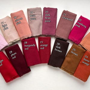 May include: A collection of fabric swatches in various colors, including pinks, reds, and browns. Each swatch is labeled with a number and color name, such as "baby pink," "burgundy red," and "dark brown." The swatches are arranged in a fan shape.