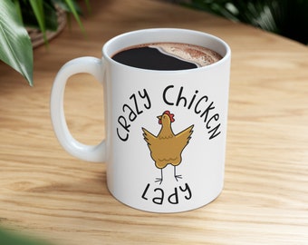 May include: White ceramic mug with a black handle. The mug has a black coffee inside and a graphic of a yellow chicken with red comb and wattle. The text "Crazy Chicken Lady" is written in black around the chicken.
