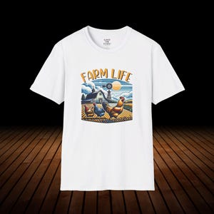 May include: White t-shirt with a graphic of a farm scene with a red barn, a windmill, and three chickens. The text "FARM LIFE" is printed in yellow above the graphic.
