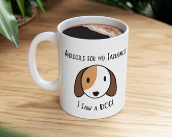 May include: White coffee mug with a brown and white cartoon dog illustration. The mug reads "Apologies for my tardiness I saw a dog!"