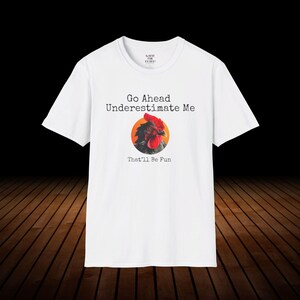 May include: White t-shirt with a black and red rooster illustration and the text "Go Ahead Underestimate Me That'll Be Fun".