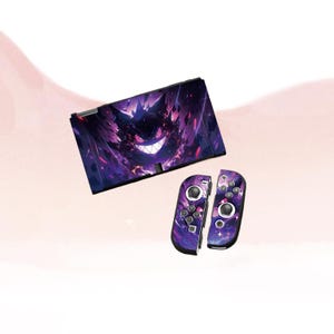 Może przedstawiać: Konsola Nintendo Switch i kontrolery Joy-Con z fioletowo-czarnym wzorem z uśmiechniętą postacią. Konsola i kontrolery mają tło o tematyce kosmicznej z gwiazdami i elementami kosmicznymi.