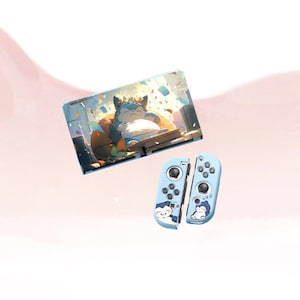 May include: A light blue Nintendo Switch console and Joy-Con controllers. The console features a graphic of a cartoon character lounging on a throne. The Joy-Cons have a matching design with a sleeping character.