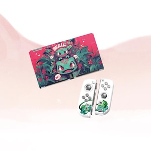 May include: A red and green Nintendo Switch case and white Joy-Con controllers. The case features a cartoon illustration of a green creature with the text "BEA!" and "BE!". The controllers have matching graphics.