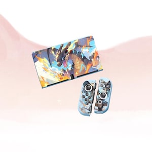 May include: A Nintendo Switch console and Joy-Con controllers in blue and white. The console has a dragon graphic with flames. The controllers have a similar design, with a blue and white colour scheme.