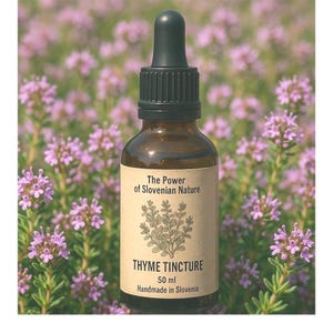 Könnte beinhalten: Eine braune Glasflasche mit Tropfer und einem Etikett mit der Aufschrift "The Power of Slovenian Nature Thyme Tincture 50 ml Handmade in Slovenia". Die Flasche steht auf einem Bett aus violetten Blüten.