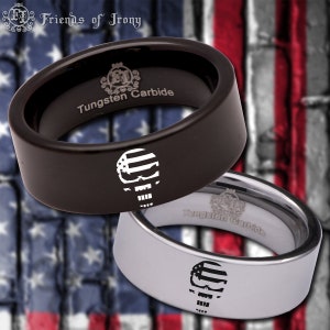 May include: Two tungsten carbide rings with a skull design. The skull is outlined with an American flag pattern. One ring is black and the other is silver.