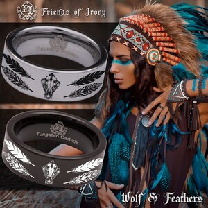 May include: Two tungsten carbide rings featuring a wolf skull and feather design. The rings are black and silver. The text "Tungsten Carbide" is visible on the inside of the rings. The rings are displayed against a background of a woman wearing a Native American headdress and jewellery.