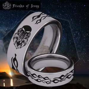 May include: Two silver tungsten carbide rings with black engraved designs. The top ring features a wolf's head with a skull and flames. The bottom ring features flames.
