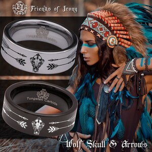 May include: Two tungsten carbide rings featuring a black and white wolf skull and arrows design. The rings are engraved with "Tungsten Carbide" and "Friends of Irony". The rings are displayed against a backdrop of a woman wearing a Native American headdress.