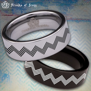 Puede incluir: Dos anillos de carburo de tungsteno con un patrón en zigzag. El anillo de arriba es plateado con un patrón negro, mientras que el anillo de abajo es negro con un patrón blanco. Los anillos están grabados con "Tungsten Carbide" y "Friends of Irony".