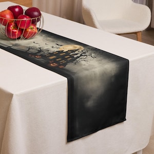 May include: A black Halloween table runner depicting a haunted house, full moon, bats, and jack-o'-lanterns. The rectangular runner is made of dark fabric, ideal for a festive holiday display, measuring approximately 180 cm in length.