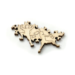 May include: A wooden jigsaw puzzle piece shaped like a stylized map of a landmass. The piece is made of light brown wood and has a smooth, polished finish.
