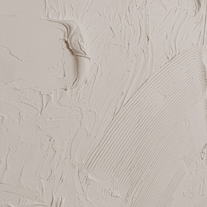 Puede incluir: Primer plano de una superficie texturizada de color blanco roto con un patr&oacute;n liso y arremolinado. La superficie tiene una textura ligeramente granulada y parece estar hecha de yeso o pintura.