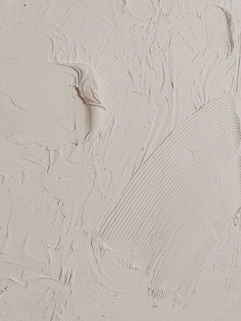 Puede incluir: Primer plano de una superficie texturizada de color blanco roto con un patr&oacute;n liso y arremolinado. La superficie tiene una textura ligeramente granulada y parece estar hecha de yeso o pintura.