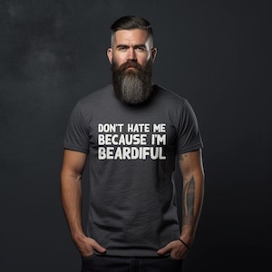 Puede incluir: Una camiseta gris oscuro con el texto "Don't hate me because I'm Beardifull" impreso en blanco.