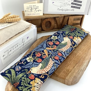 May include: A patterned eye pillow with a bird and berry design on a wooden board. The image includes a box labeled "Mindfulness" and a card that reads "the best things in life are made with love." Other items include a box and the word "LOVE."