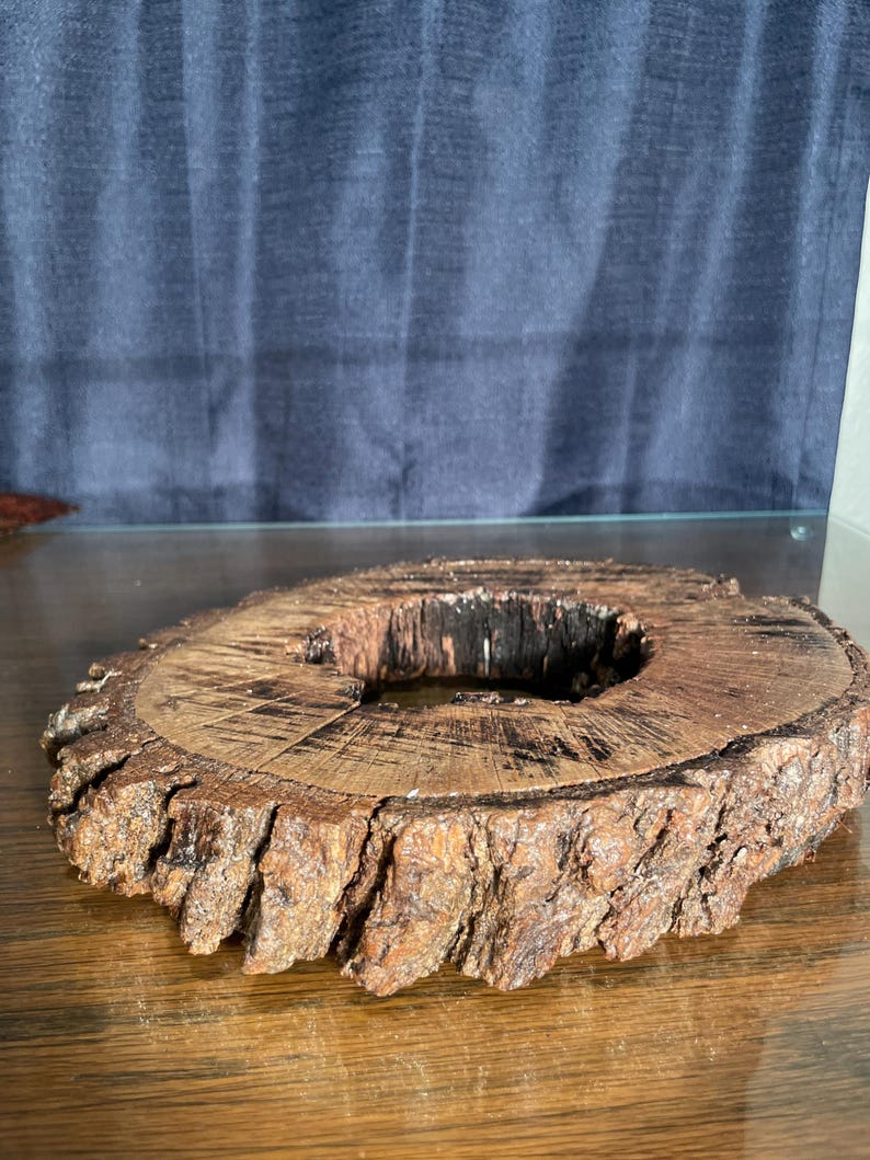 May include: A rustic wooden ring with a natural bark edge and a hole in the center. The ring is brown and has a rough texture.