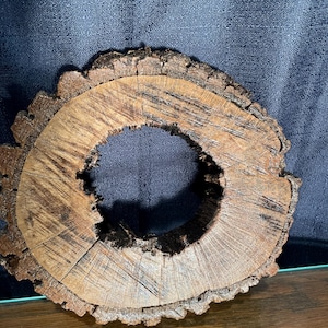 May include: A rustic wooden ring with a natural brown finish and a rough, textured surface. The ring has a large hole in the center and is perfect for adding a touch of nature to your home decor.