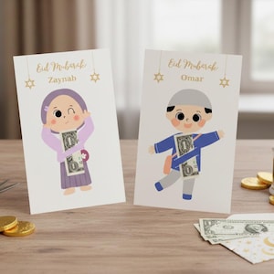 May include: Two greeting cards with cartoon illustrations of children holding money. The cards read "Eid Mubarak" with the names "Zaynab" and "Omar". Gold stars and a decorative lantern are also visible.