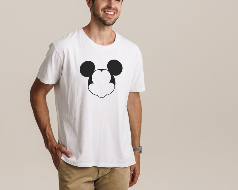以下が含まれることがあります： 白地に黒と白のミッキーマウスの顔のグラフィックがプリントされたTシャツ