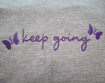 May include: Gray sweatshirt with purple embroidered butterflies and the text "keep going".