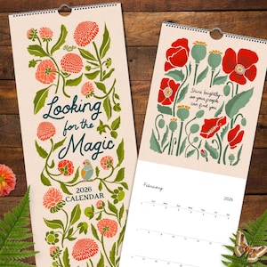 May include: Two 2026 wall calendars with floral designs. One features the text "Looking for the Magic" and the other has red poppies and the quote "Shine brightly so your people can find you." Both have a spiral binding.