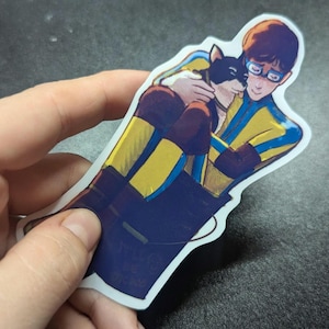 May include: A sticker featuring an illustration of a person hugging a black and brown dog. The person is wearing a yellow and blue outfit, and the dog has a black face. The sticker has a white border.