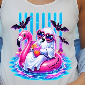 Può includere: Una canotta bianca con la grafica di un fantasma bianco che indossa occhiali da sole a forma di cuore, seduto su un salvagente a forma di fenicottero rosa mentre tiene in mano una bevanda tropicale. Il design include tre piccoli pipistrelli.