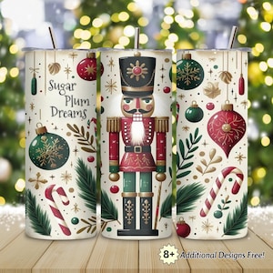May include: A set of three insulated tumblers with a festive Christmas theme. Each tumbler features a different design, including a nutcracker, ornaments, candy canes, and the text "Sugar Plum Dreams". The tumblers have a silver straw.