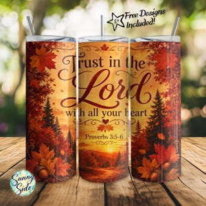 May include: A cylindrical tumbler with a straw featuring an autumn forest scene with orange and red maple leaves, pine trees, and a sunset. The text reads Trust in the Lord with all your heart Proverbs 3:5-6. A star icon says 8+ Free Designs Included.