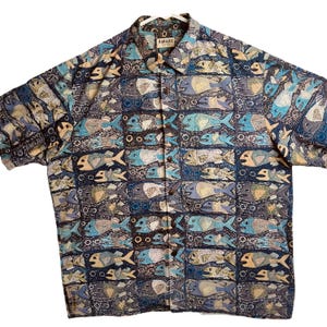 May include: A blue, brown, and yellow short-sleeved button-down shirt with a fish pattern. The shirt has a label that says "KAHALA".