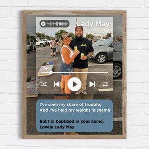 May include: A framed print with a Spotify-style graphic for the song "Lady May" by Tyler Childers. The image shows a couple and song lyrics. The frame is a light brown colour.