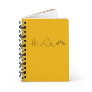 May include: A yellow spiral bound notebook with a simple line drawing of trees, a mountain, and a sun on the front cover.