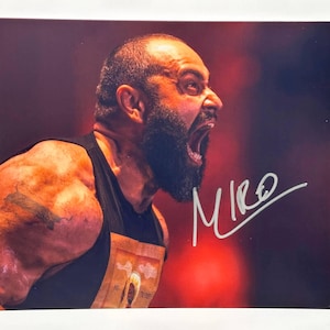 May include: A signed photograph featuring a muscular man with a bald head and a full beard, screaming with his mouth wide open. The man is wearing a black tank top. The signature "Miro" is visible in the lower right corner.
