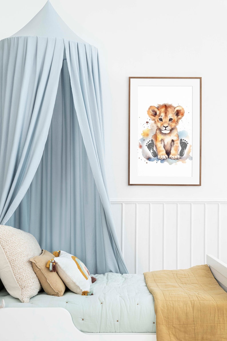 May include: A watercolor painting of a cute lion cub sitting on a cloud with paw prints. The painting is framed in a light brown frame and is hanging on a white wall.