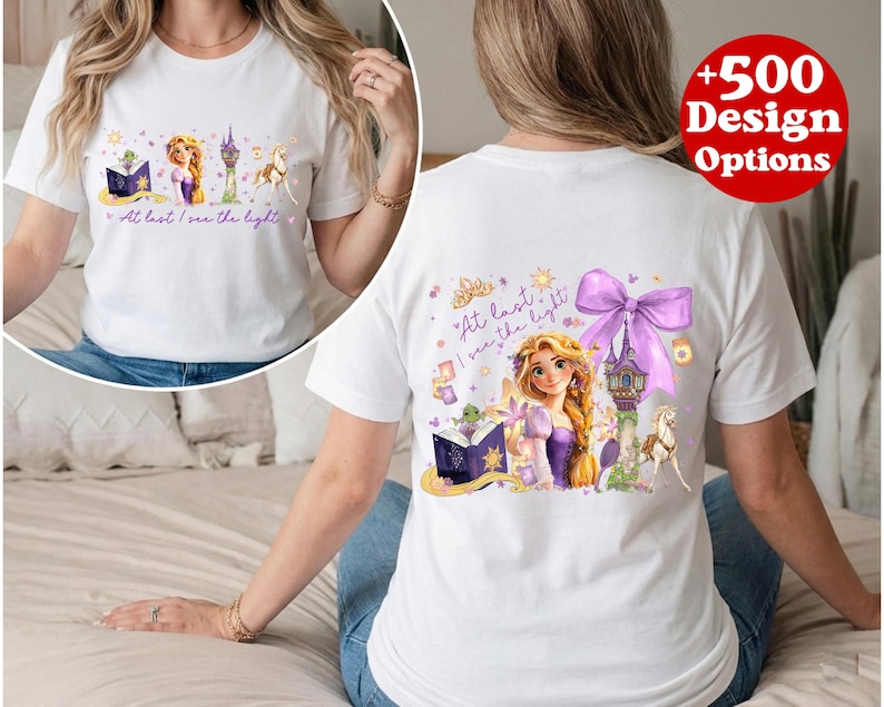 Puede incluir: Camiseta blanca con un gr&aacute;fico colorido de una princesa, una torre y un caballo. El texto "At last I see the light" est&aacute; impreso. Tambi&eacute;n es visible un c&iacute;rculo rojo con "+500 Design Options". Dise&ntilde;o de cuento de hadas.