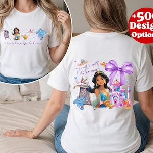 Puede incluir: Camiseta blanca con una colorida ilustraci&oacute;n de una princesa, una alfombra m&aacute;gica, un genio y un palacio. Tambi&eacute;n se muestra el texto "I'm not a prize to be won!". La camiseta tiene cuello redondo y mangas cortas.