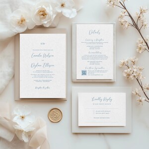 Peut inclure: Un ensemble de faire-part de mariage comprenant une invitation principale, une carte de détails et une carte de réponse. Les invitations présentent une écriture bleu clair sur un fond texturé blanc cassé. Un sceau de cire doré et des éléments floraux complètent le design.