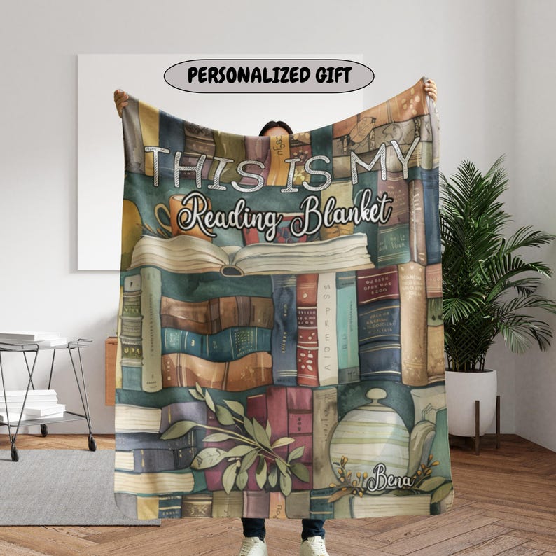 May include: A cozy blanket featuring a design of stacked books in various colors. The blanket has the text "THIS IS MY Reading Blanket" and "PERSONALIZED GIFT" in a banner. The blanket is a perfect gift for book lovers.