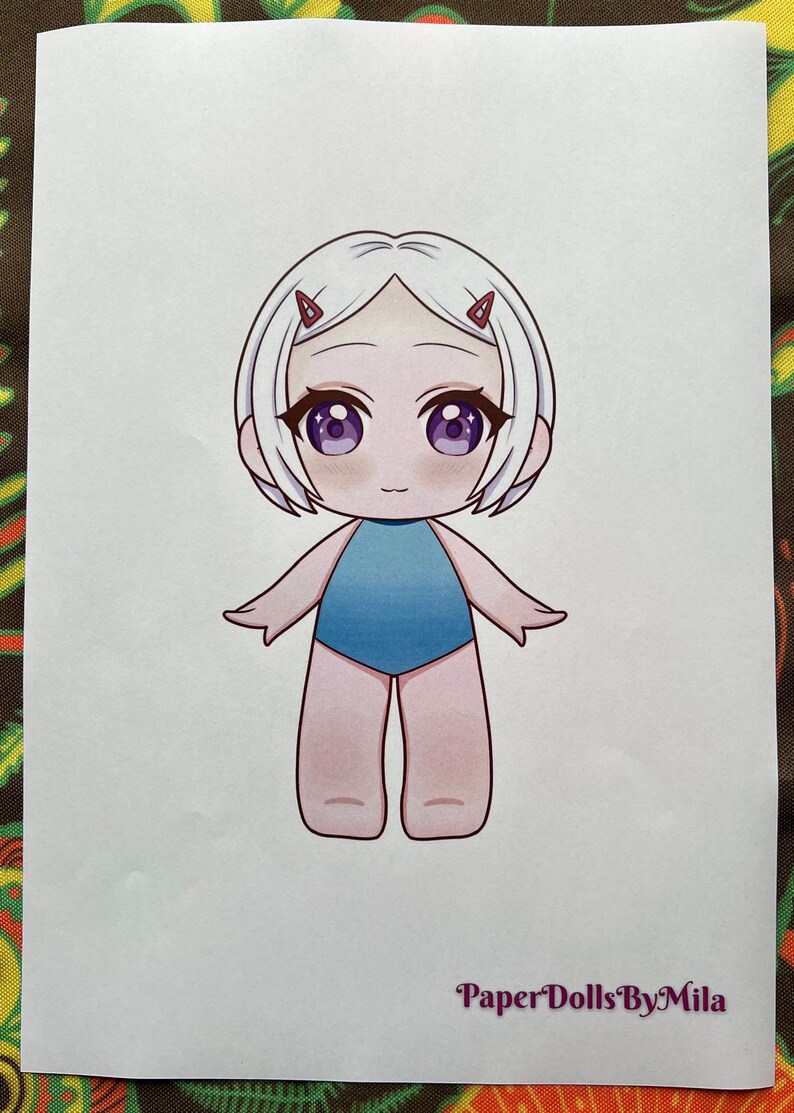 May include: A cartoon illustration of a doll with white hair, purple eyes, and a blue swimsuit. The doll has small red hair clips. The text "Paper Dolls By Mila" is printed at the bottom.