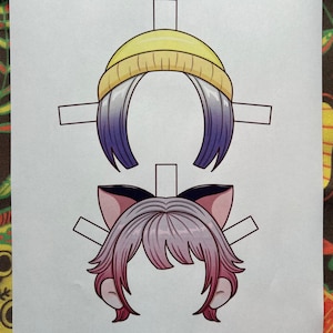 May include: Two paper doll hair styles are shown. The top one has a yellow beanie and purple and white hair. The bottom one has pink hair and cat ears. The text "Paper Dolls By Mila" is at the bottom.