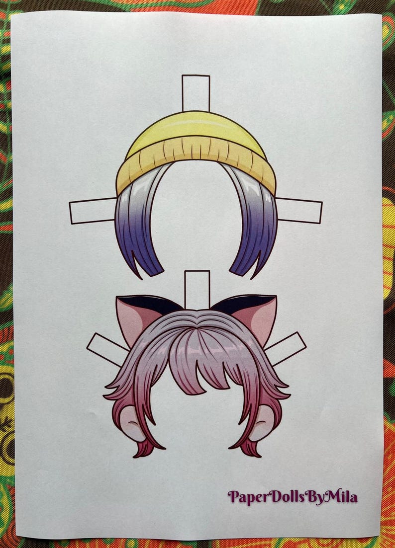 May include: Two paper doll hair styles are shown. The top one has a yellow beanie and purple and white hair. The bottom one has pink hair and cat ears. The text "Paper Dolls By Mila" is at the bottom.