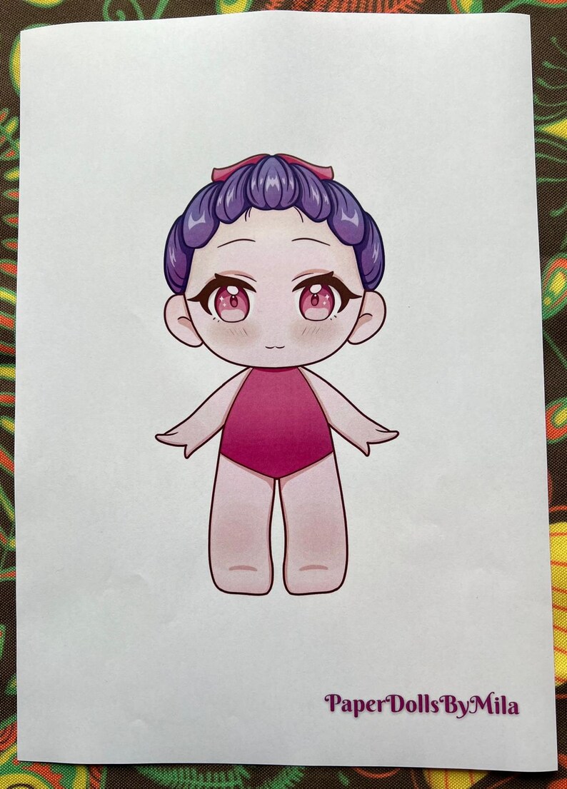 May include: A paper doll illustration of a cartoon character with purple hair and a pink swimsuit. The character has large, pink eyes and a small smile. The text "Paper Dolls By Mila" is at the bottom.