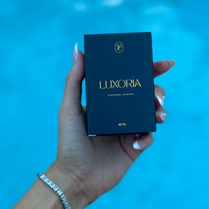 May include: A black box with gold lettering that reads "LUXORIA DIAMOND SHIMMER" and "40 ML".