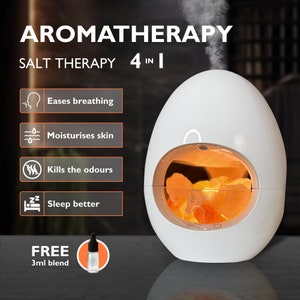 Può includere: Diffusore di aromaterapia bianco a forma di uovo con una lampada di sale incorporata. Il diffusore ha una finestra trasparente che mostra i cristalli di sale arancioni all'interno. Il diffusore ha due pulsanti sul fondo, uno per la luce e uno per la nebbia. Il testo "LUXOCUR" è visibile sui cristalli di sale. Il testo "AROMATHERAPY SALT THERAPY 4 IN 1" è nella parte superiore dell'immagine. Sotto il diffusore ci sono quattro icone con testo: "Eases breathing", "Moisturises skin", "Kills the odours" e "Sleep better". Il testo "FREE 3ml blend" è nella parte inferiore dell'immagine.
