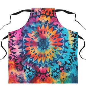 May include: A colorful tie-dye apron with a large circular pattern in shades of pink, orange, yellow, blue, and green. The apron has black adjustable straps.