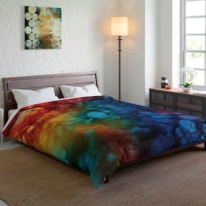 Peut inclure: Une housse de couette abstraite colorée avec un arc-en-ciel de couleurs, y compris le rouge, l'orange, le jaune, le vert, le bleu et le violet. La housse de couette a un effet tie-dye avec un motif tourbillonnant.