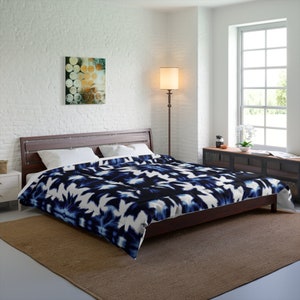 May include: A blue and white patterned duvet cover with a modern abstract design. The duvet cover is on a bed with a wooden frame and a brown rug.